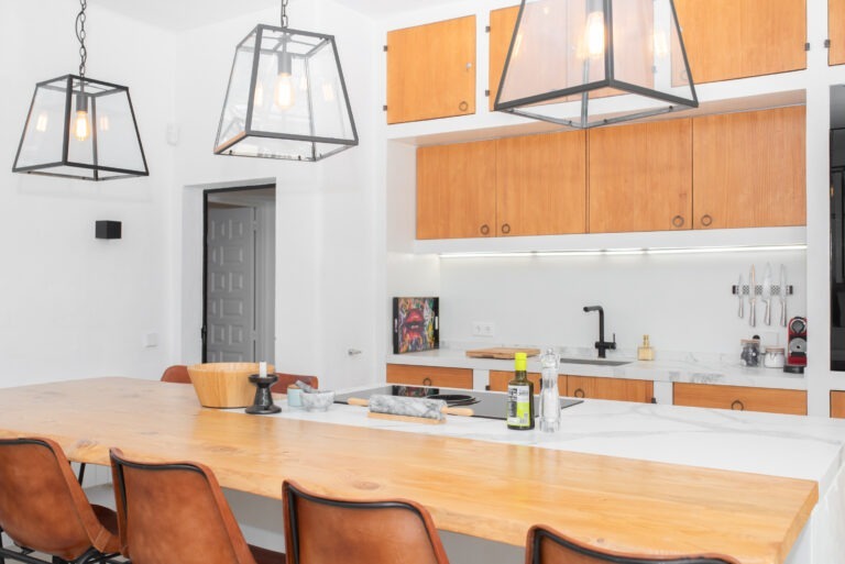 Can Petit's kitchen dining table with tan leather stools under black cage pendants