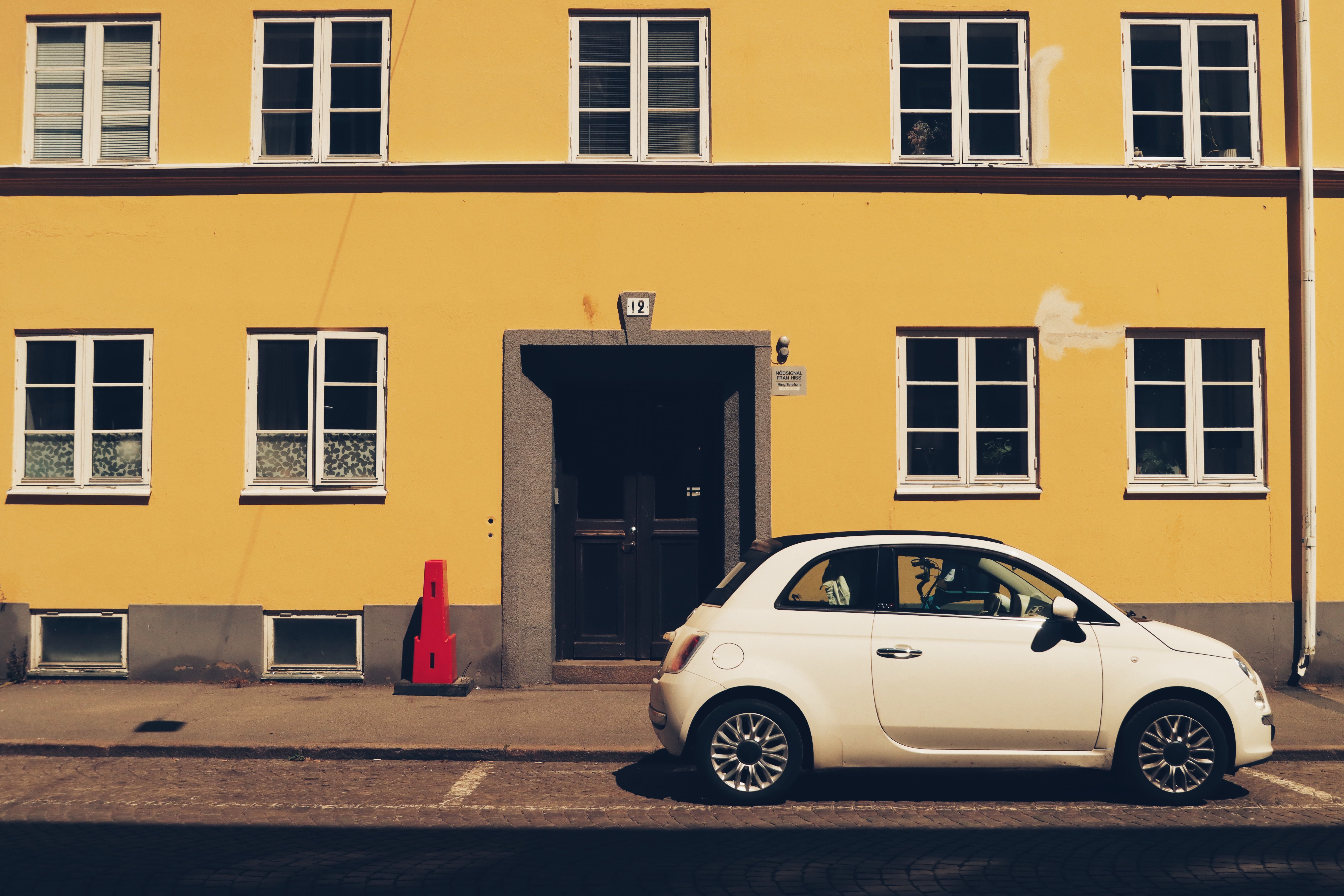Compact white rental car parked in front of a yellow building