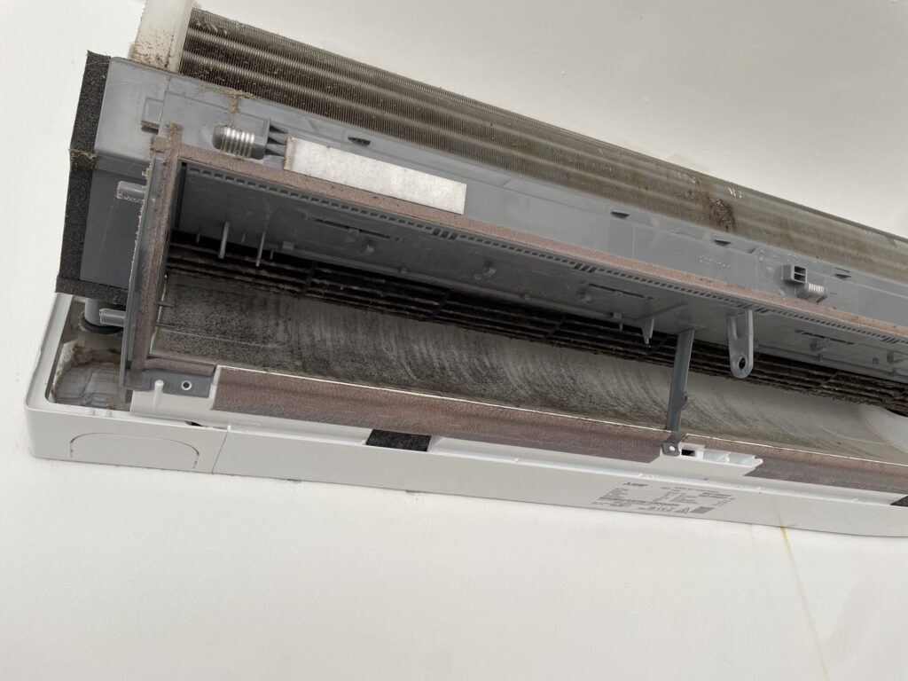 Dirty evaporator coil of a wall-mounted air conditioning unit in an Ibiza rental villa, opened for cleaning