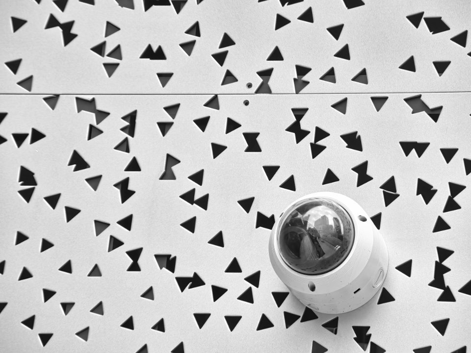 White dome security camera mounted on a white perforated wall panel